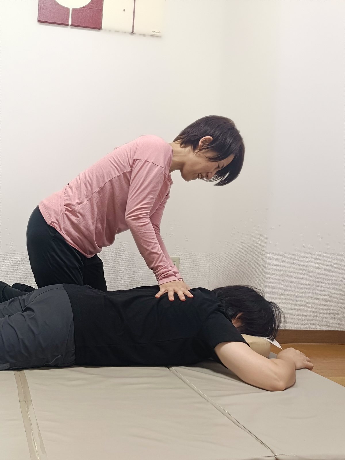 うつ伏せになった生徒の背中に、あすすが手を当てている様子